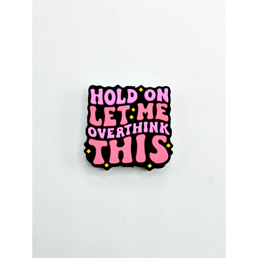 A rectangular silicone bead with the text 'HOLD ON LET ME OVERTHINK THIS' written in pink, with added yellow details.