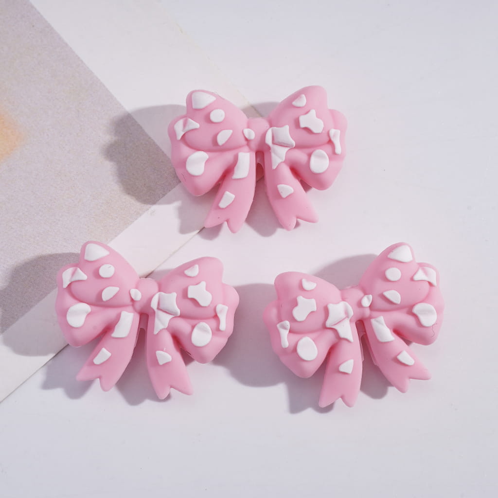 Three pink hair bows with white polka dots on a light background