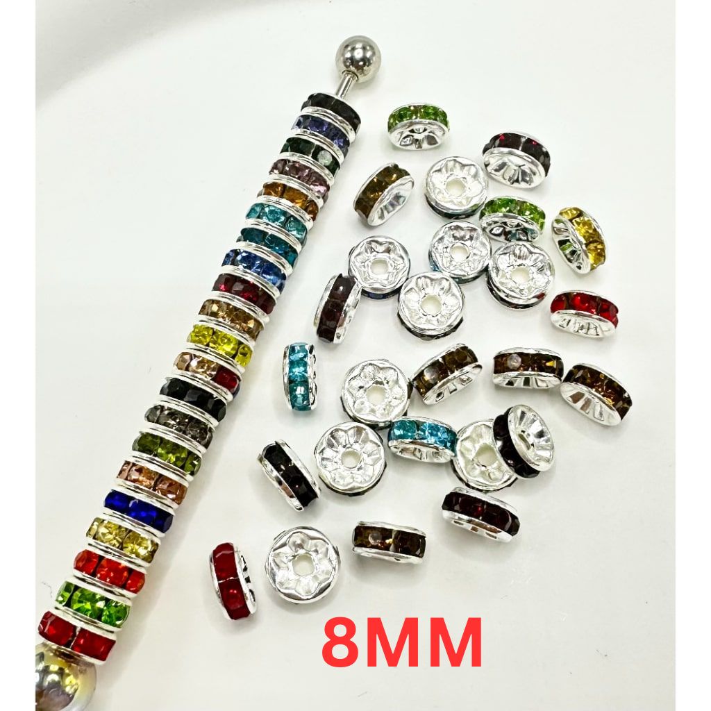 A collection of flat round metal spacers with rhinestones in various colors, predominantly silver-colored with an 8mm size label visible.