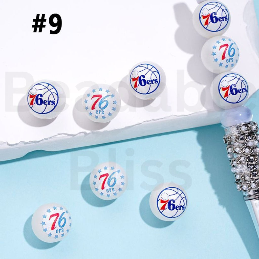 Philadelphia 76ers logo on small round stickers with a decorative pen on a light blue background.