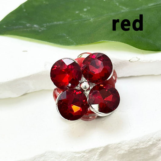 A collection of colorful flower-shaped beads with rhinestones and pearls, displayed on a white surface.

