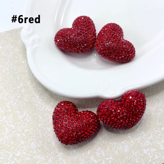 An assortment of heart-shaped clay beads embedded with multicolored rhinestones.

