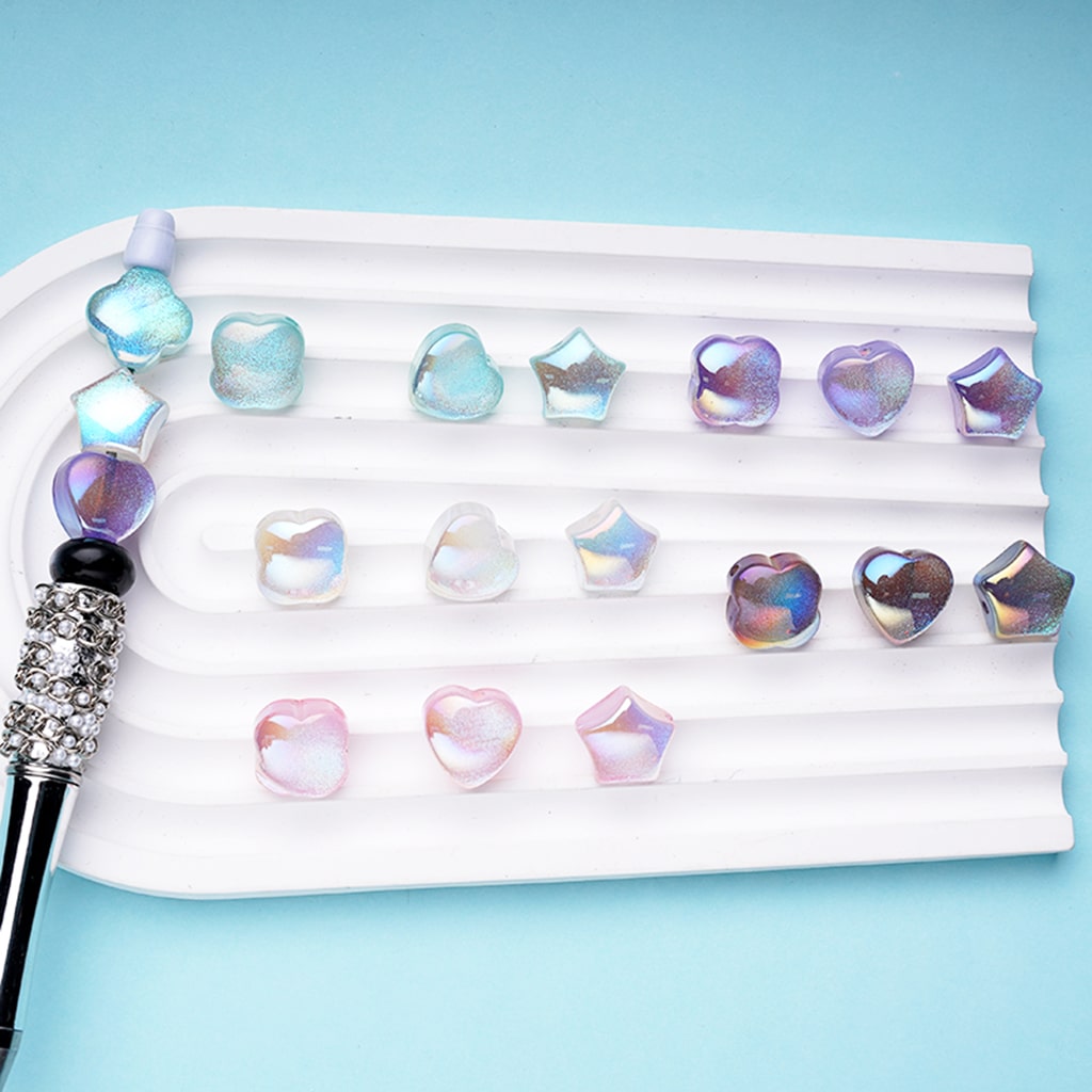 An assortment of colorful clear acrylic beads in star, heart, and clover shapes displayed on a white surface with a blue background.

