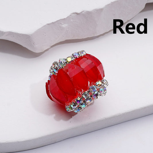 Red heart-shaped jewelry piece with gemstones on a light background

