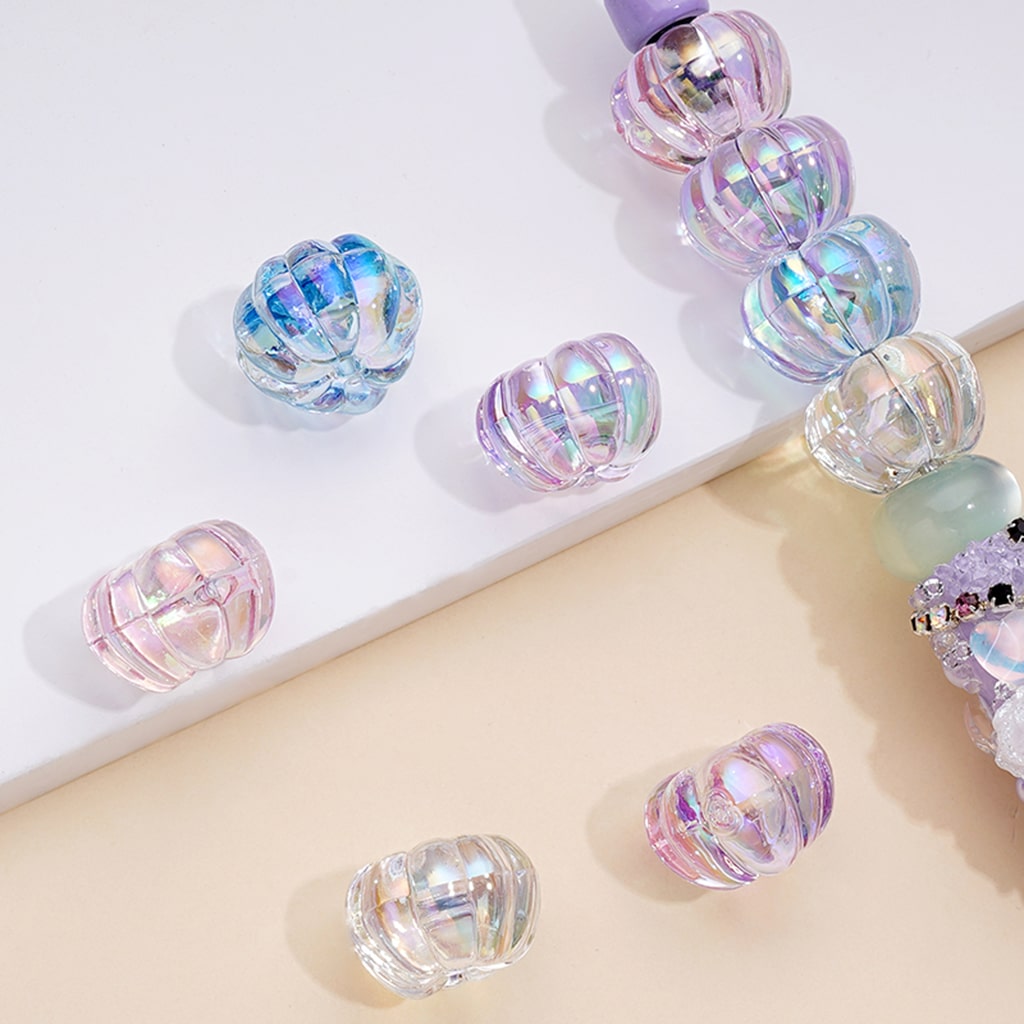 A collection of translucent pumpkin-shaped UV coating acrylic beads in various colors including orange, yellow, green, purple, and blue.

