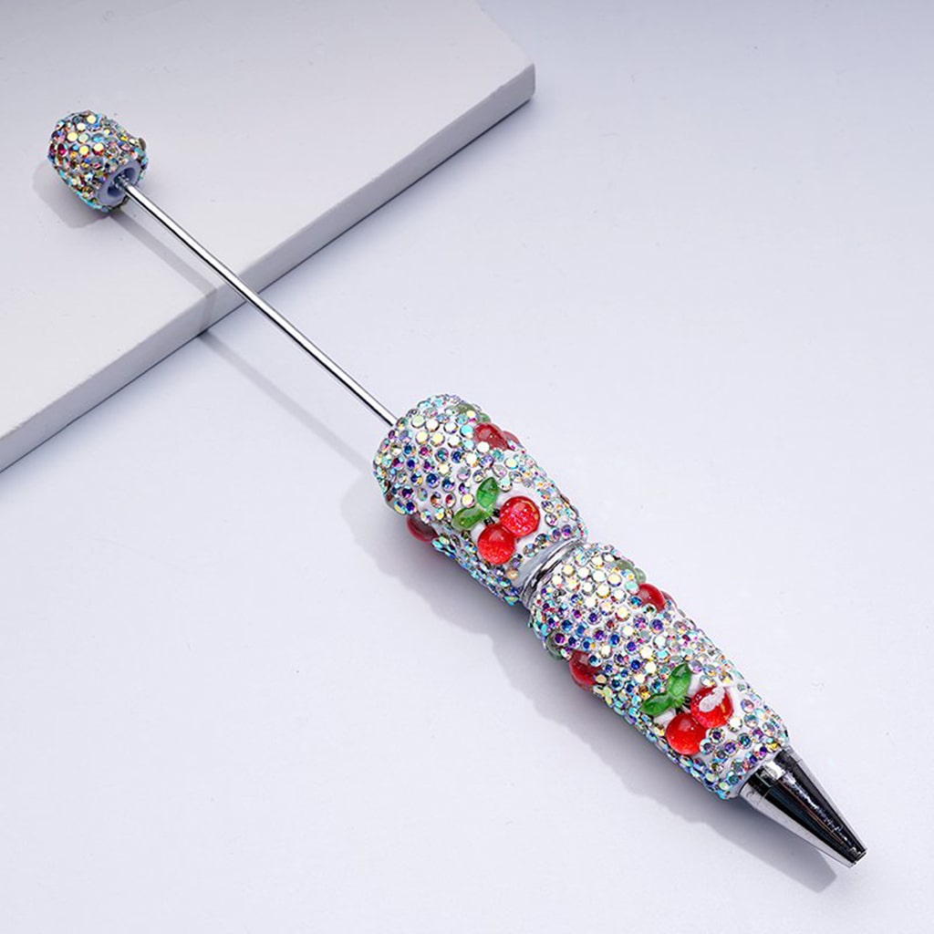 Decorative pen with gemstones and cherry designs on a light background