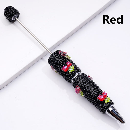 Decorative pen with black beads and red floral accents on a white background

