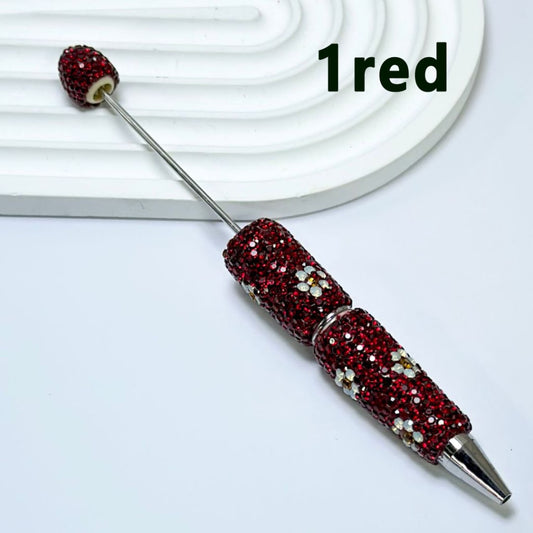 A collection of pens with multicolored rhinestones and flower embellishments, displayed on a white surface.

