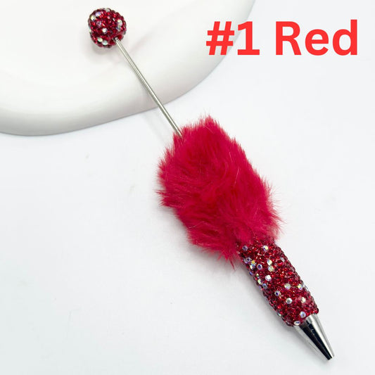 A selection of pens with fluffy pom pom toppers and rhinestone decorations, in various colors.

