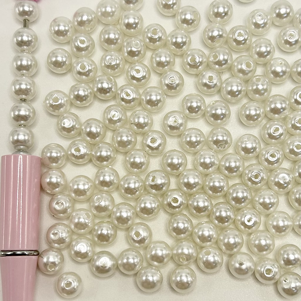 White pearls with a pink pen on a white background
