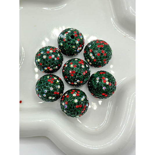 Green beads with red and white specks on a white dish