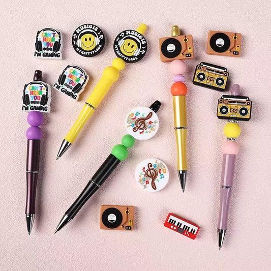 A collection of pens and silicone beads designed to look like various musical instruments, including earphones and cassettes.

