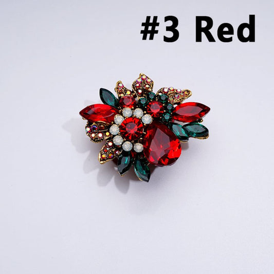 A collection of gold alloy flower-shaped brooches with various colorful rhinestones and white pearls, displayed against a white background.

