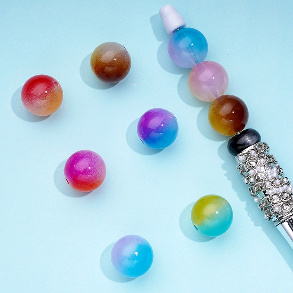 Colorful beads and a decorative pen on a light blue background

