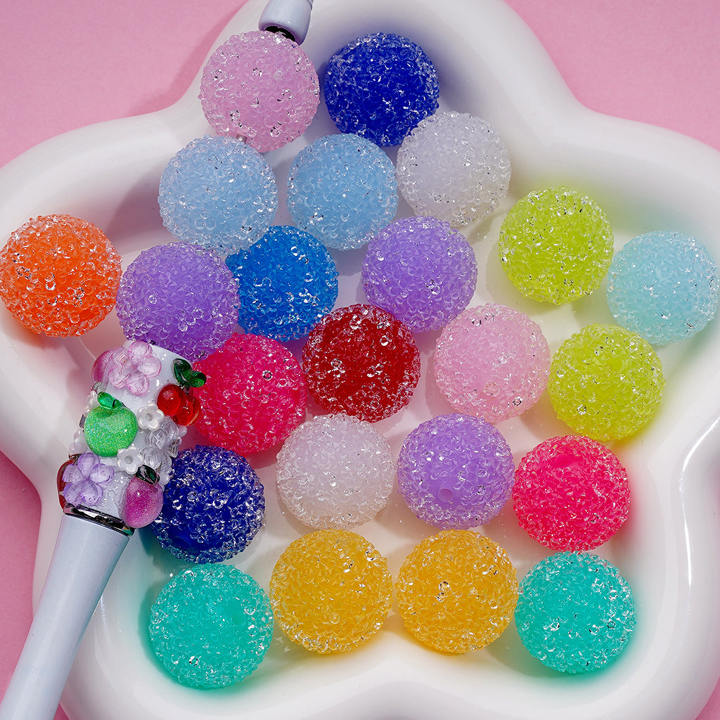 A collection of colorful round hard sugar beads with a glittery finish, displayed in a variety of colors including blue, purple, pink, red, white, green, orange, and yellow.

