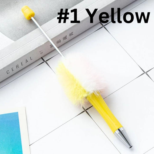 A selection of pens each with a different color fluffy pom pom attached to the top, displayed on a white surface.

