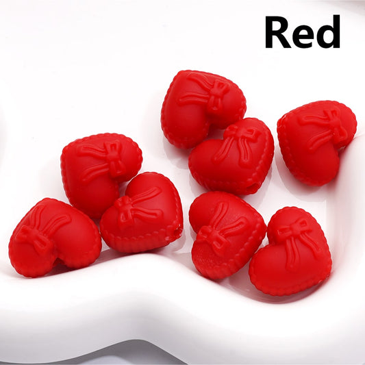 Red heart-shaped objects with bows on a white background


