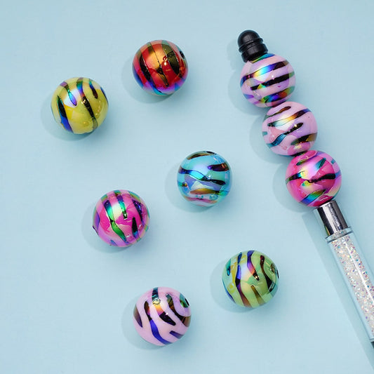 Colorful beaded pen and beads on a light blue background

