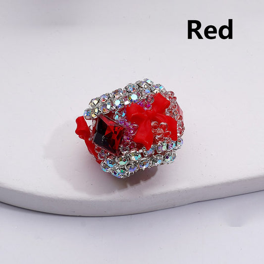 Decorative ring with red bow and gemstones on a white background

