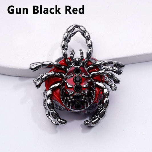 Scorpion-shaped pendant with red and black design on a white background

