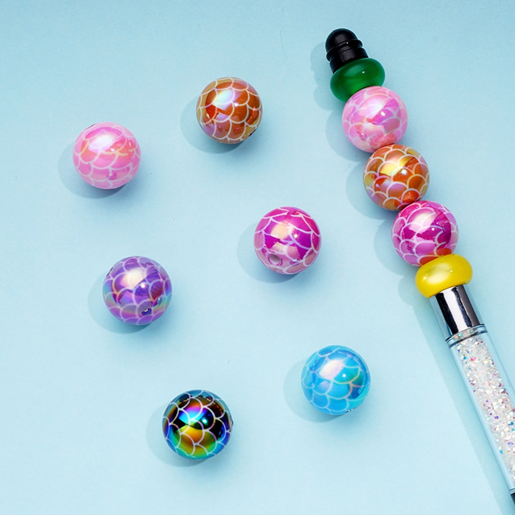Colorful beaded pen with various beads on a light blue background

