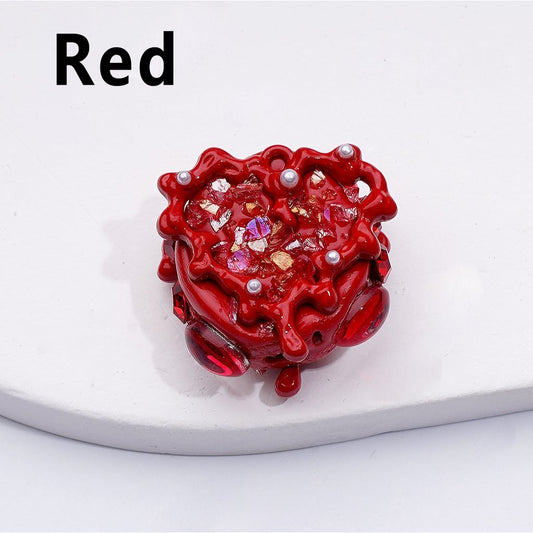 Red decorative item with embedded pearls and crystals on a white surface

