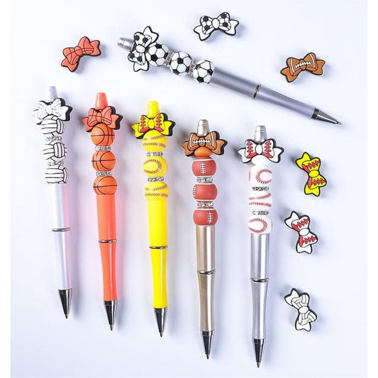 A collection of pens and pens with silicone beads in the shape of sports balls, including basketball, volleyball, baseball, soccer, and football designs.

