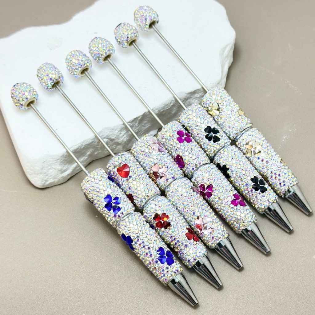 Set of decorative pens with gemstone accents on a stone surface