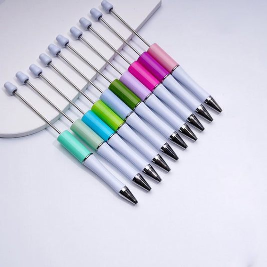 A selection of double-color beadable pens in various colors with silver beads attached to them.

