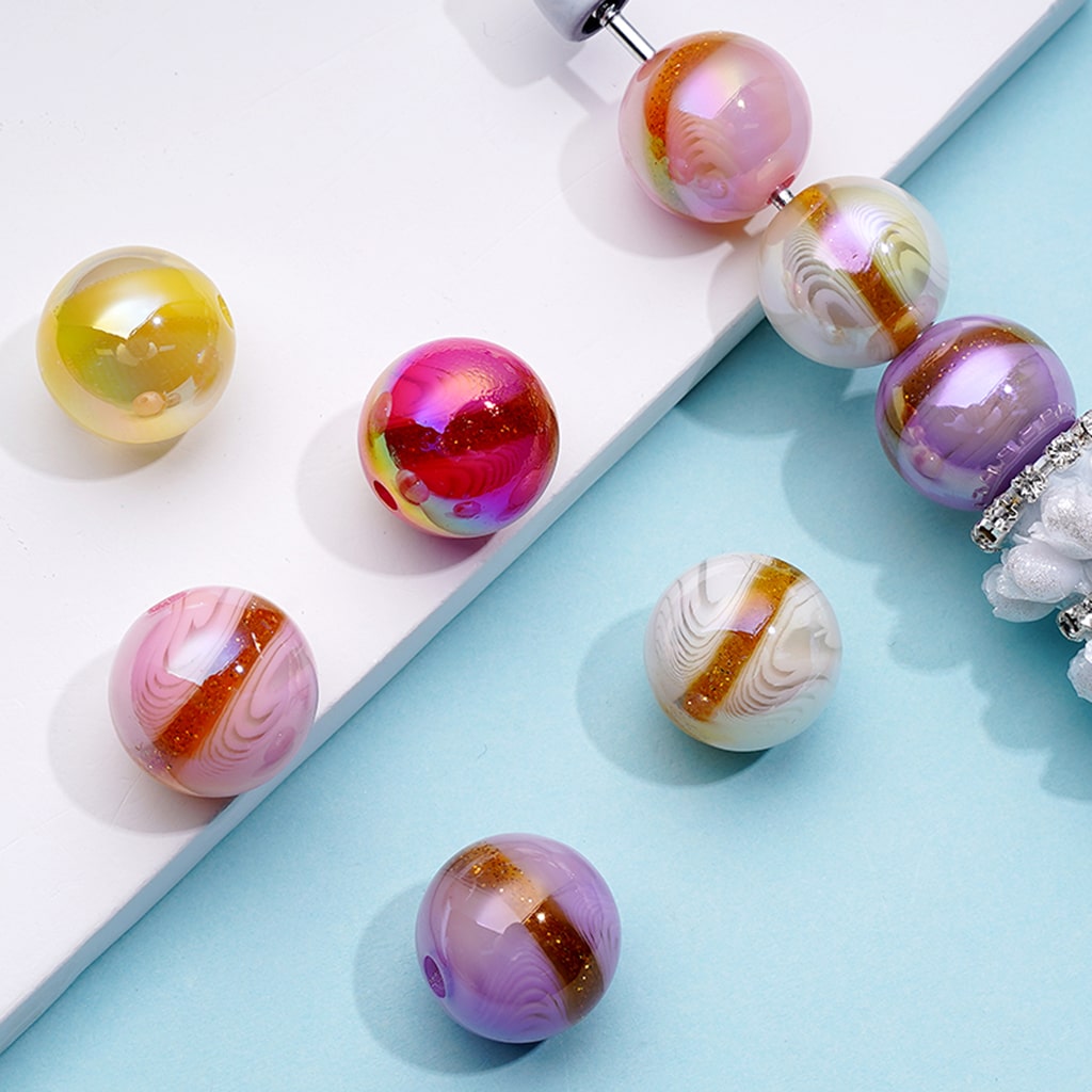 A collection of round acrylic beads in gold glitter with star river pattern, displayed on a flat surface.

