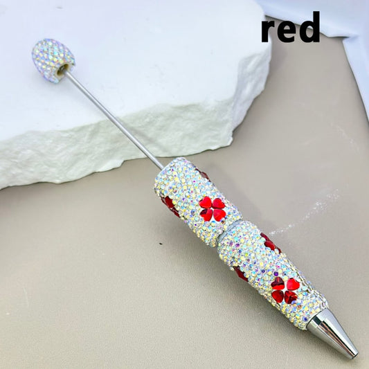 Decorative pen with gemstones and red flowers on a beige surface