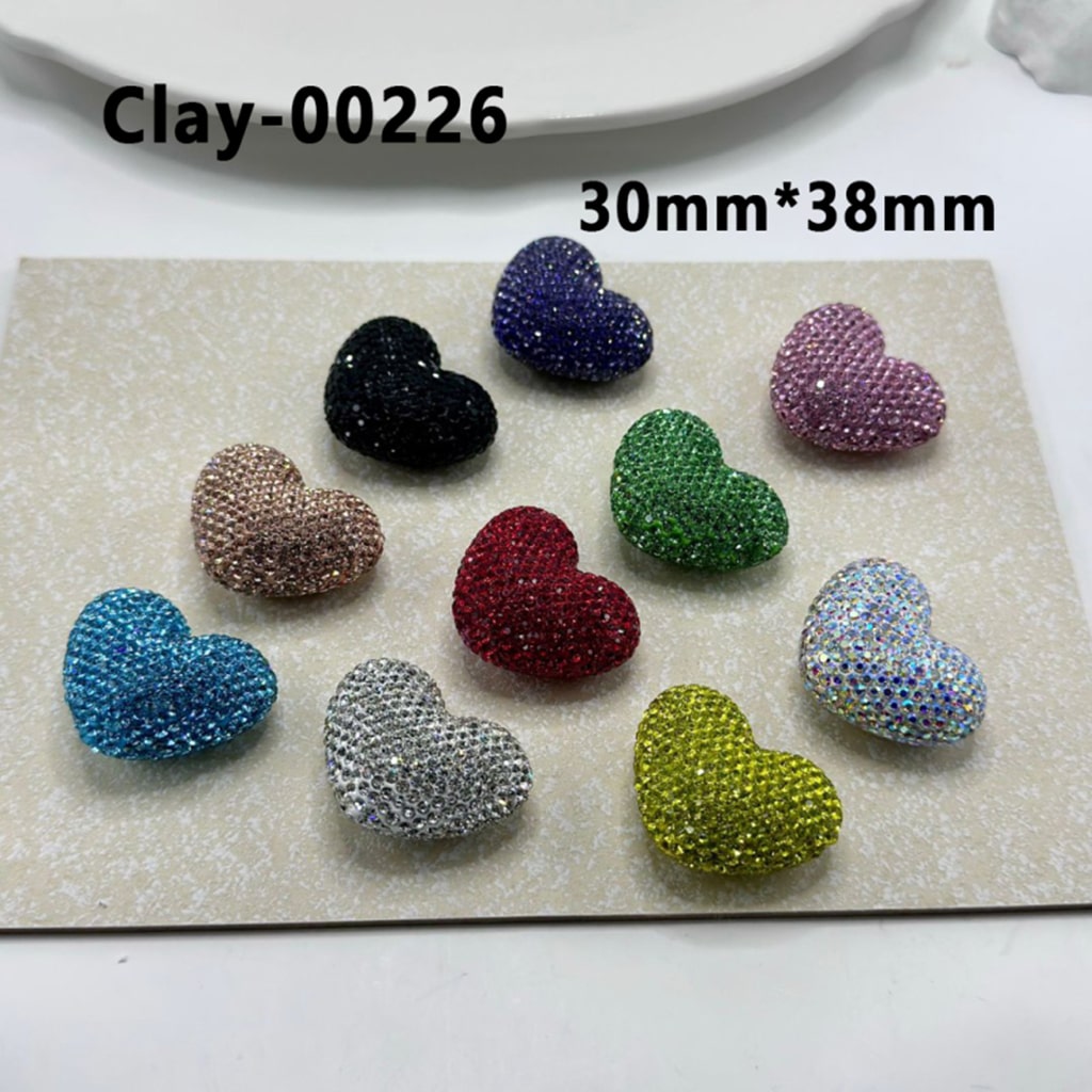 A collection of heart-shaped clay beads in various colors, each adorned with colorful rhinestones. The beads are approximately 30mm by 38mm in size.

