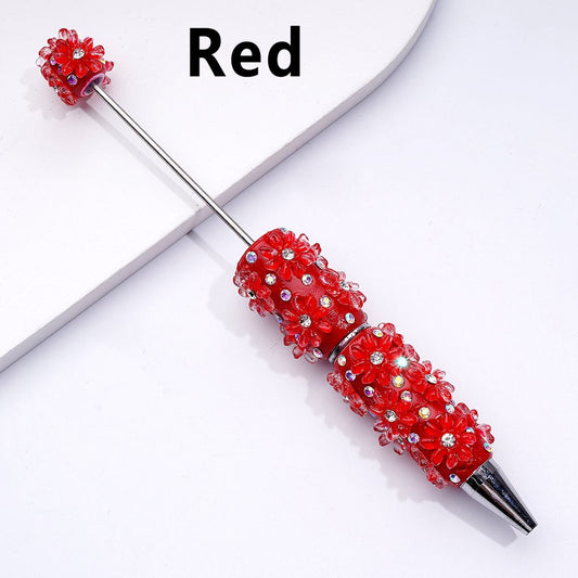 Decorative pen with red bead embellishments on a white background

