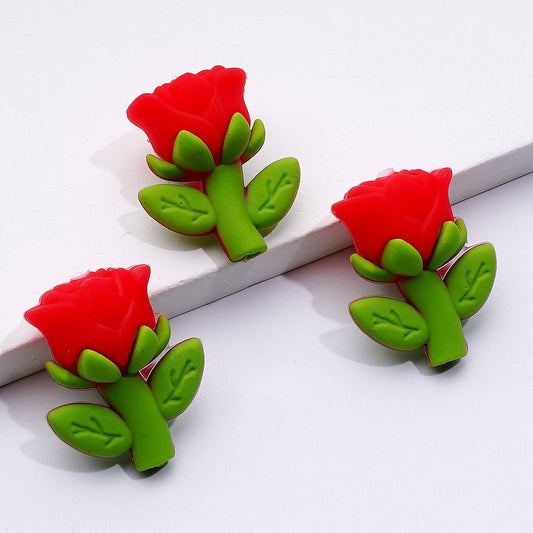 Red rose-shaped hair clips with green leaves on a white background

