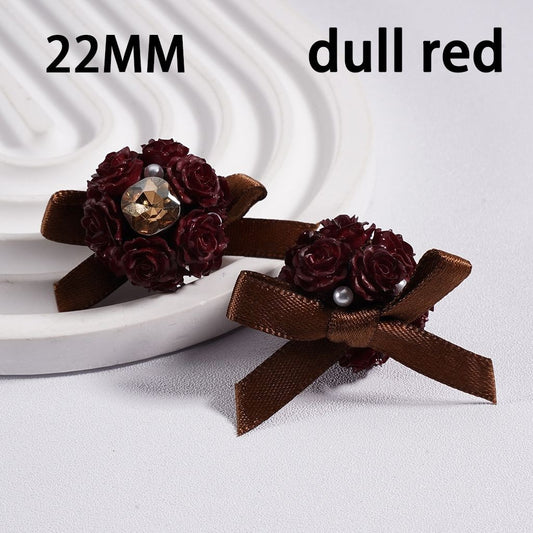 Pair of earrings with brown ribbons and dark red flowers on a white background