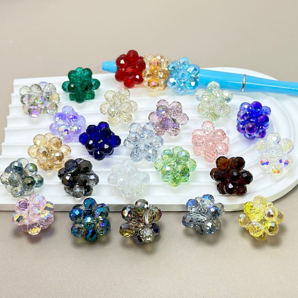 Assorted colorful flower-shaped beads on a white tray with a beige background

