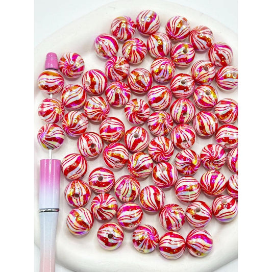 Pink and white marbled beads with a pink tool on a white background

