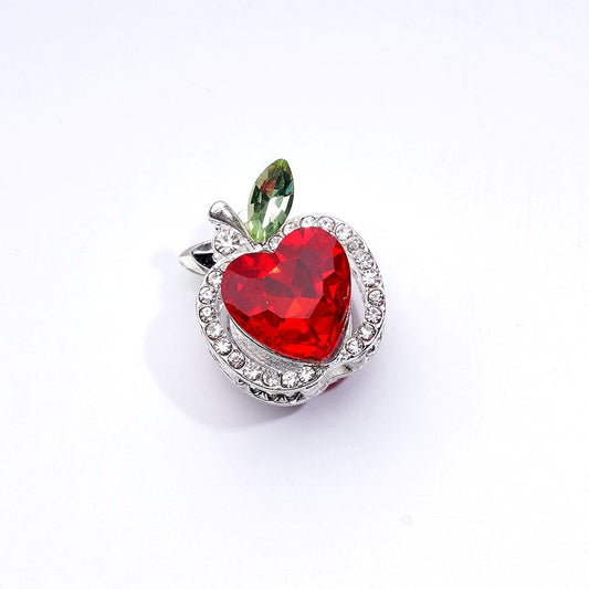 Red heart-shaped crystal charm with green leaf on a white background

