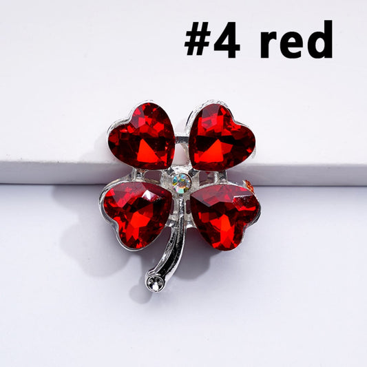 A collection of silver-colored alloy beads shaped like four-leaf clovers, each with a multicolored heart-shaped rhinestone in the center.

