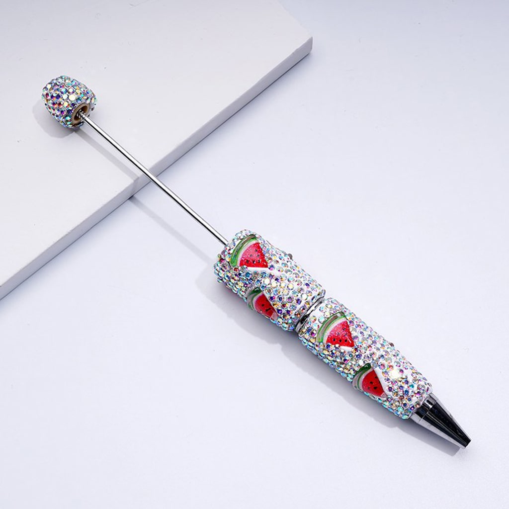 Decorative pen with watermelon design and gemstones on a white background