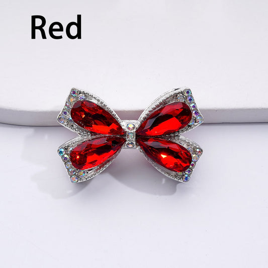 Bow-shaped jewelry with red gemstones on a white background

