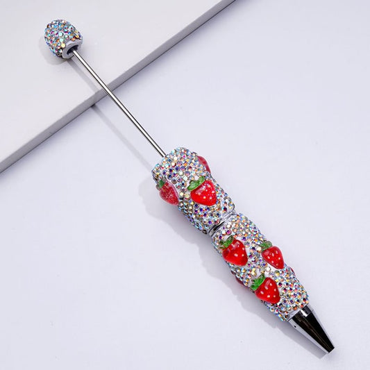 Decorative pen with strawberry design and gemstones on a white background
