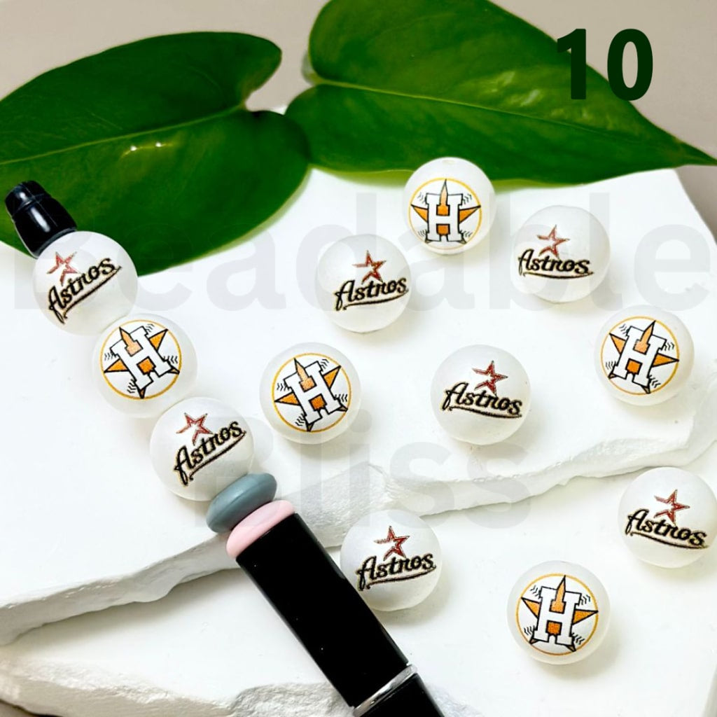 Set of Houston Astros-themed lip balms on a white surface with green leaves in the background

