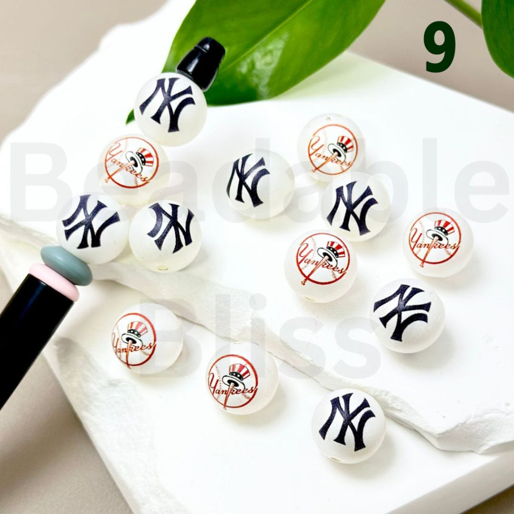 White earrings with New York Yankees logo on a white surface with green leaves in the background

