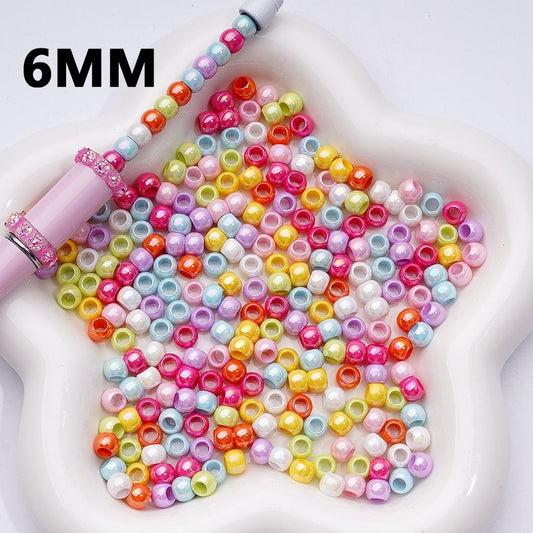Colorful beads and a tool on a white surface with '6MM' text.


