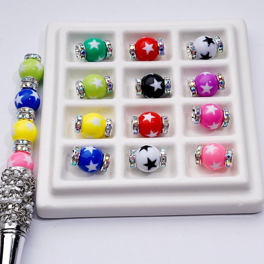 Set of colorful beads with star designs in a white display case, with a silver pen on a light gray background.

