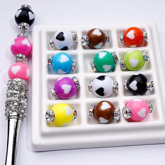 Set of colorful beads with heart patterns on a white tray

