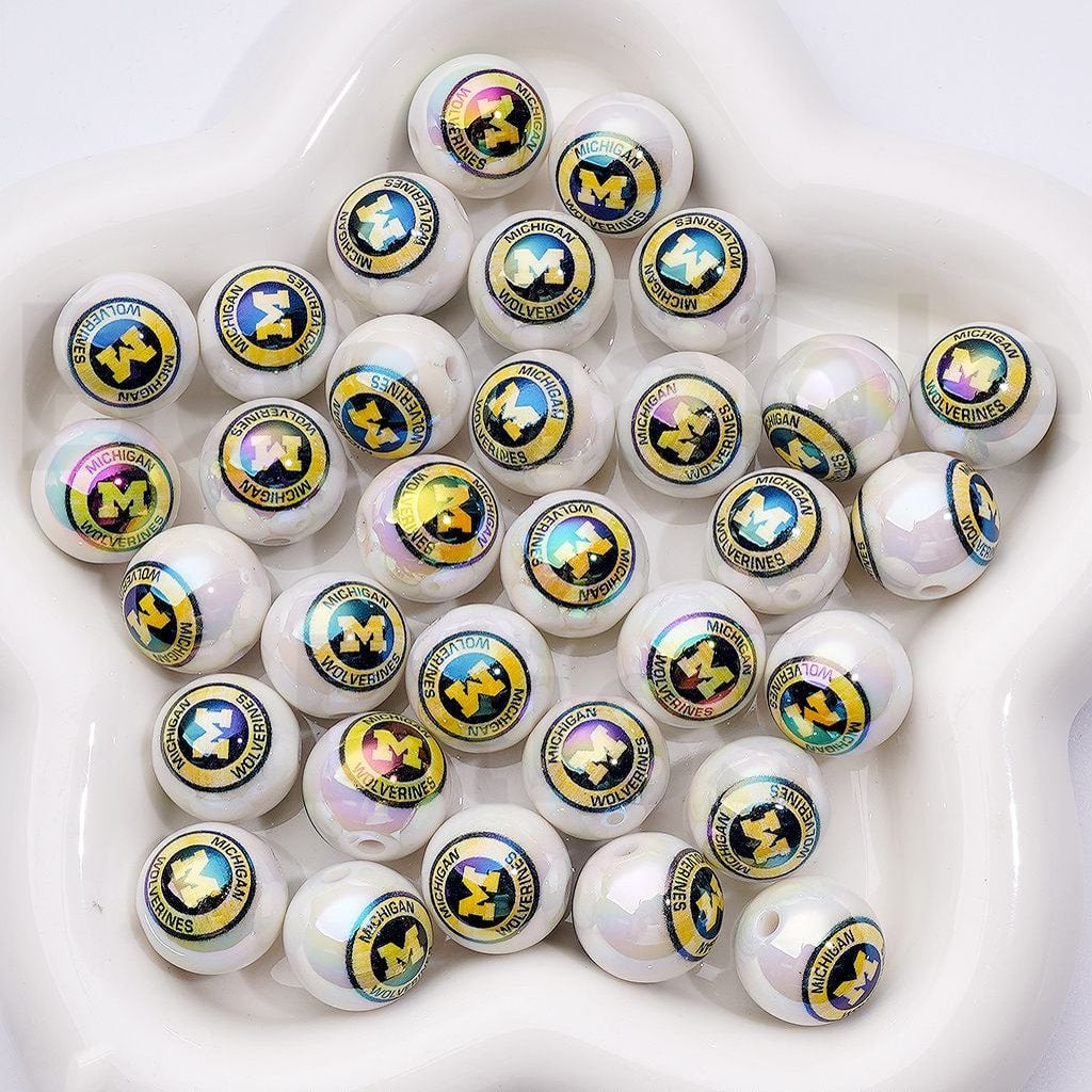 Multiple small round objects with Michigan Wolverines logo on a white surface


