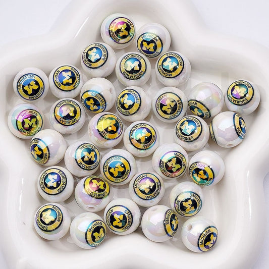 Multiple small round objects with Michigan Wolverines logo on a white surface

