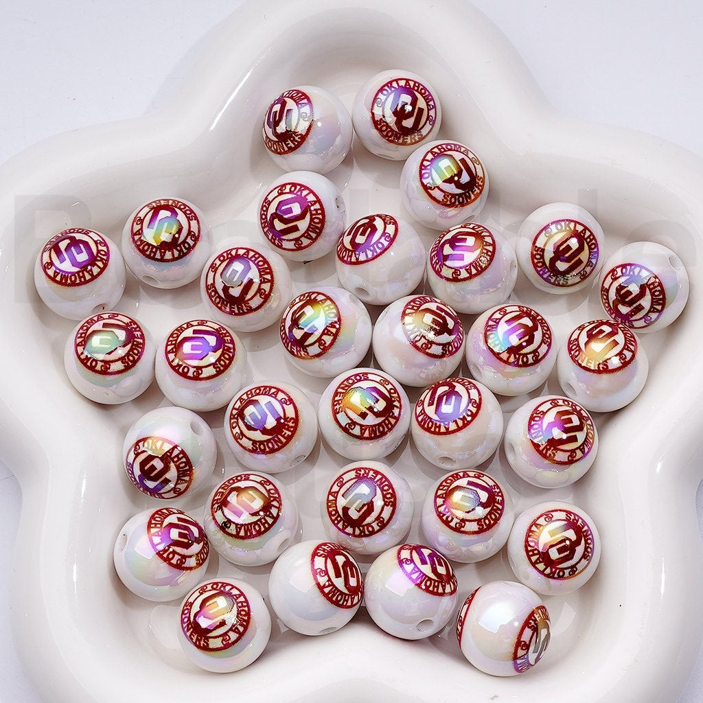 White beads with red and gold designs on a white background


